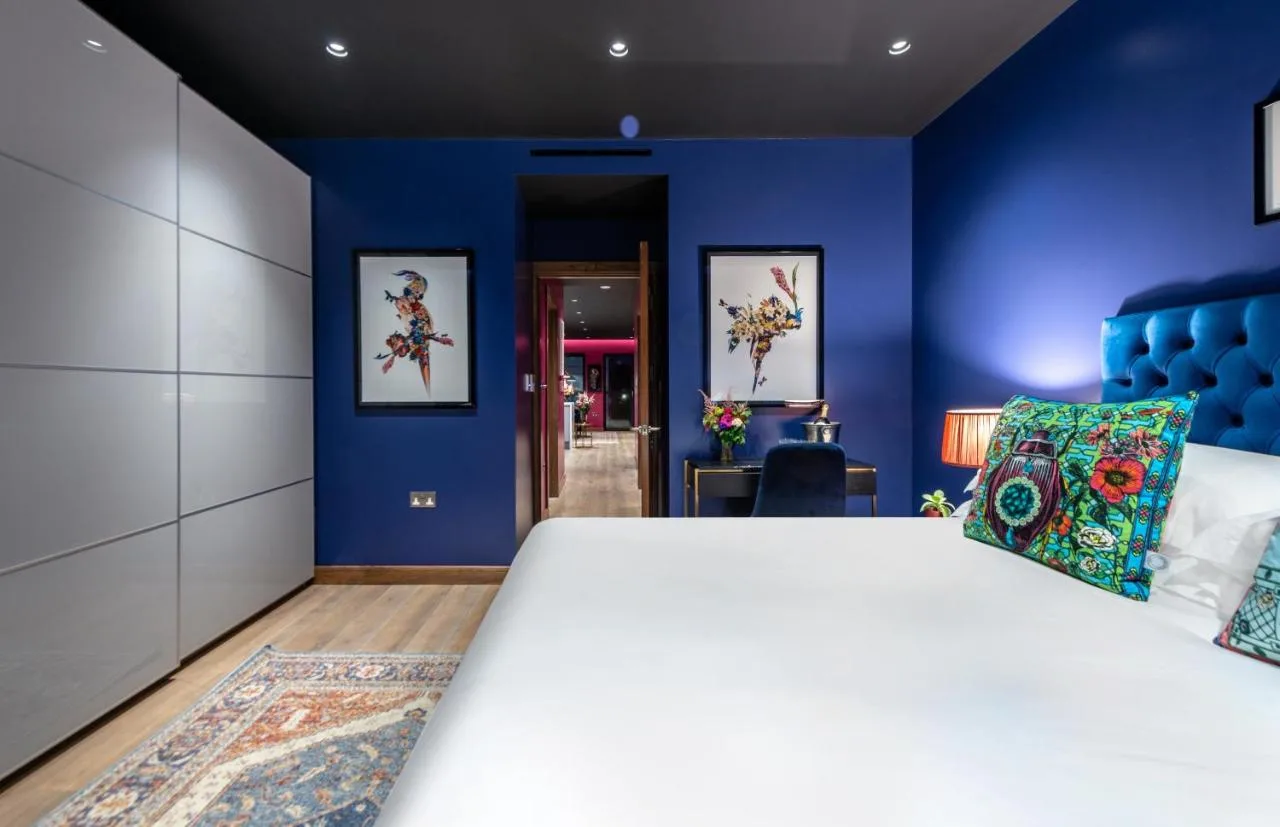 Bedroom with large white bed and blue walls at Hux Hotel, Kensington