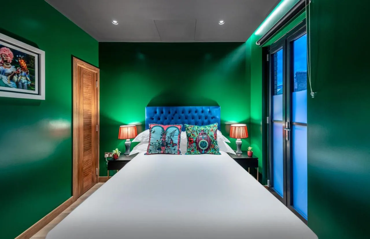 Bedroom with green walls and large bed at Hux Hotel, Kensington