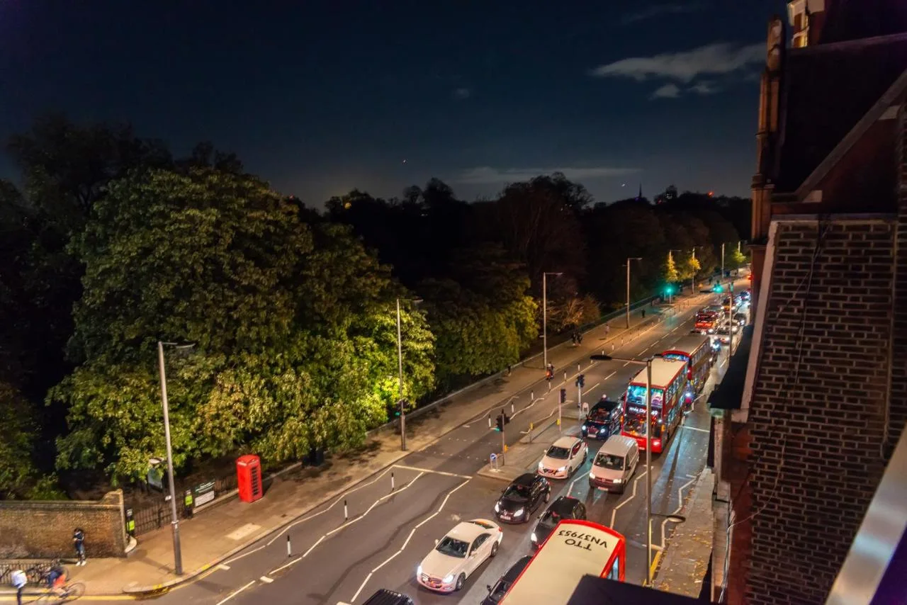 Kensington street lined with parked cars at night near Hux Hotel